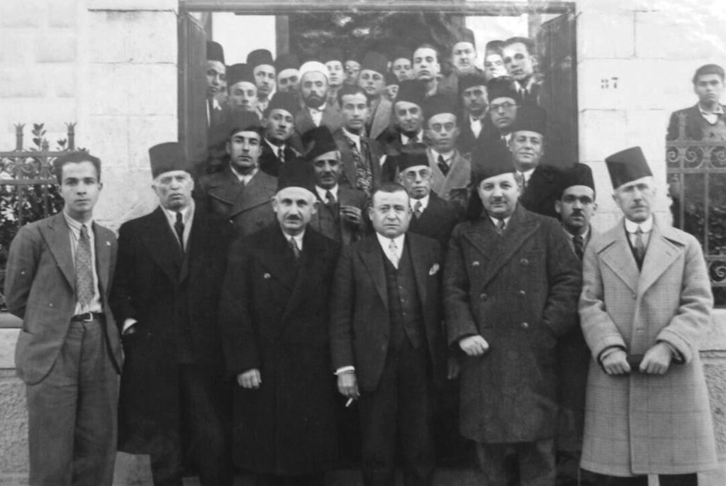 The reception of the Syrian delegation returning from Paris after concluding the 1936 treaty with the French government, on foot from the Baghdad Station to the Baron Hotel. Rushdi al-Kikhya and Mikhail Ilyan, organizers of the celebration and the procession. The leaders of the country receive the Syrian delegation after the conclusion of the treaty with France in 1936. In the picture Rushdi al-Kikhya is behind President al-Atassi. In the second row: Emir Mustafa al-Shihabi (Governor of Aleppo), Jamil Mardam, Hashim al-Atassi, Faris al-Khouri, Saadallah Jabiri, Edmond Homsi (minister and deputy for Aleppo). In the third row appear: Dr. Hasan Ibrahim Pasha, Rushdi al-Kikhya, Jamil Ibrahim Pasha and Abd al-Wahhab Muyassar.